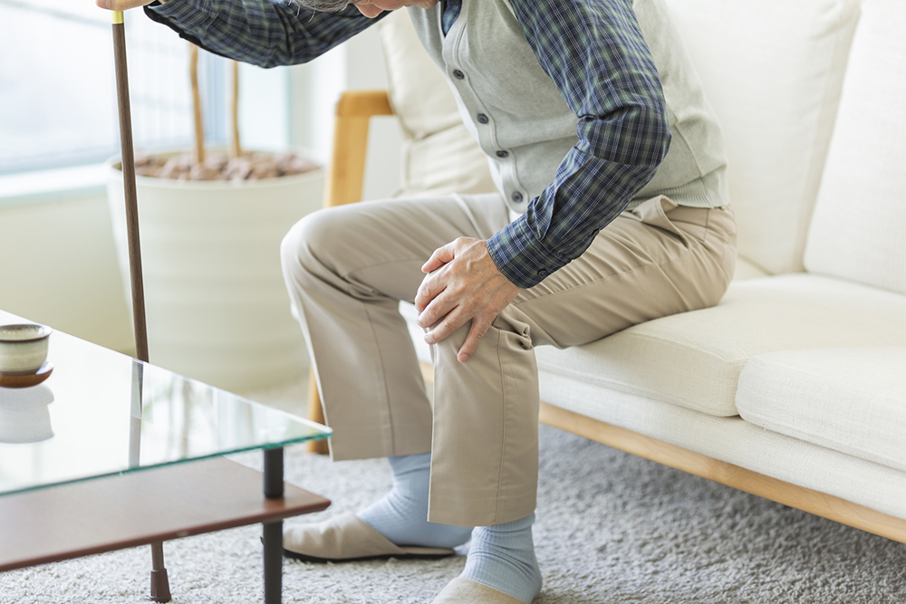 膝の痛みで杖を使う高齢者のイメージ